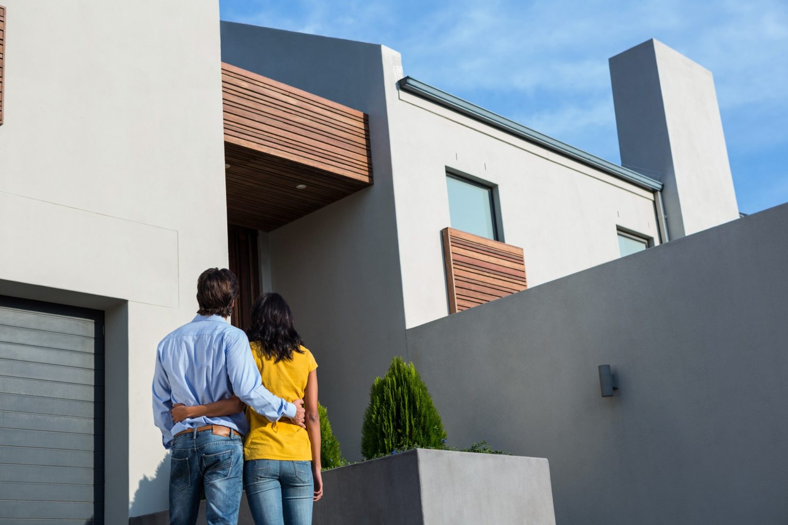 Happy Hispanic couple standing and looking at the new house